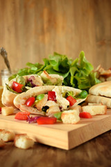 Caesar salad in pita bread on a wooden board