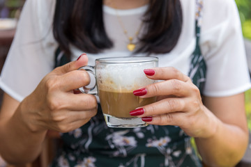 Woman holding Cappuccino coffee in hands