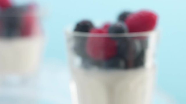 two glasses of greek yougurt with berries turning out from camera to blur zone Minimalism food video