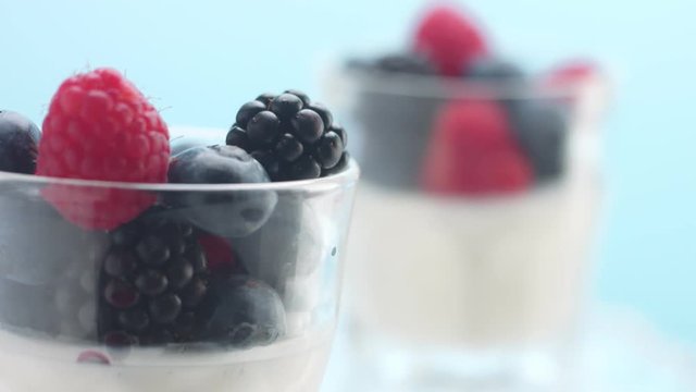 fresh breakfast with yougurt and berries on blue background. Minimalism food video