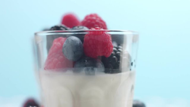 c,loseup of berries and glasses with greek yogurt on blue background. Minimalism food video