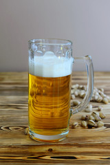 glass of beer with pistachios on a wooden background