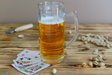 glass of beer with playing cards and pistachios