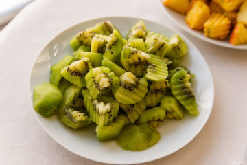 Sliced kiwi on the white plate on the yellow background.Top view