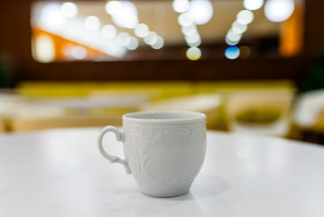 White Cup on the white table and a blurred background.