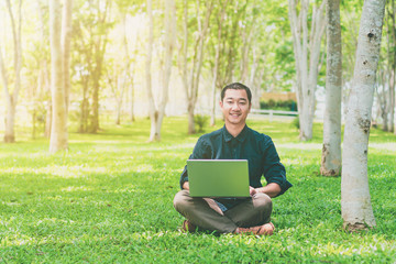 Happy asian young businessman with laptop celebrating success.