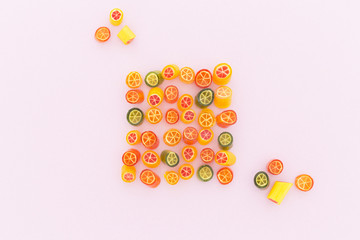 Assortment of colorful sweet handmade candy pieces arranged on light pink paper