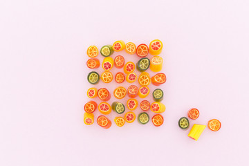 Assortment of colorful sweet handmade candy pieces arranged on light pink paper