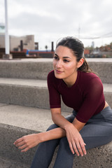 Sporty young brunette sitting on stairs