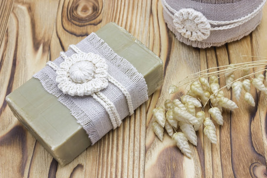 Handmade, natural organic olive oil soap and cosmetic salt on wooden background. Spa bath accessories, feminine care products. Hygiene concept photo. Herbal vaginal soap bar and scrub, crochet decor.