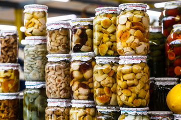 Pickled mushrooms in glass jars on the market.
