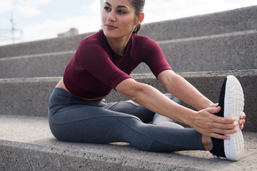 Pretty young female stretching on stairs