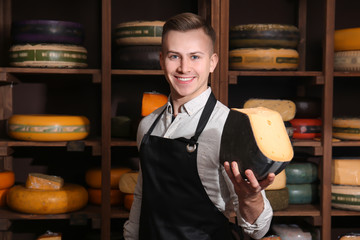 Young worker holding cheese in shop