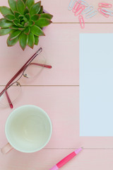 Woman desk with pink pen, coffee cup, glasses and succulent