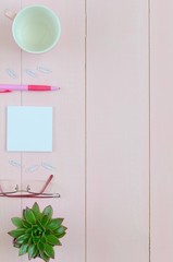 Woman desk with pink pen, paper, coffee cup, glasses and succulent