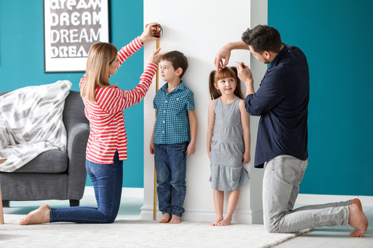 Parents measuring height of their children at home
