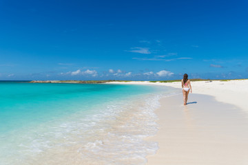 Fototapeta na wymiar Beautiful girl walking in a caribbean beach in Los Roques Venezuela