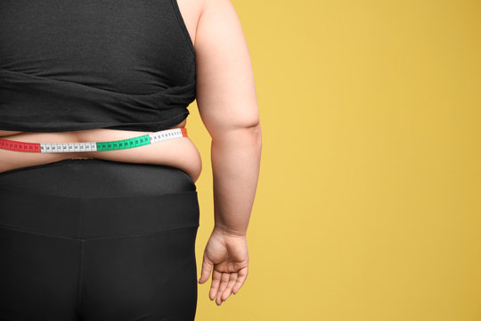 Overweight woman with measuring tape on color background