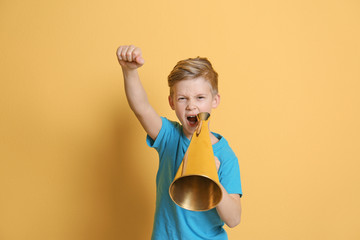 Cute little boy with megaphone on color background