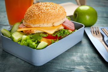 Lunch box with tasty sandwich on wooden table