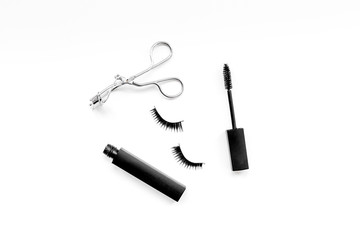 Cosmetics and tools for voluminous lashes. Mascara, false eyelashes, eyelash curler on white background top view space for text