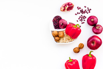 Diet for healthy heart. Food with antioxidants. Vegetables, fruits, nuts in heart shaped bowl on white background top view copy space