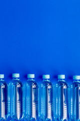 Drinking water in bottles on blue background top view copy space