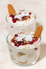 delicious dessert in a glass with cookies, cream and jam, vertical