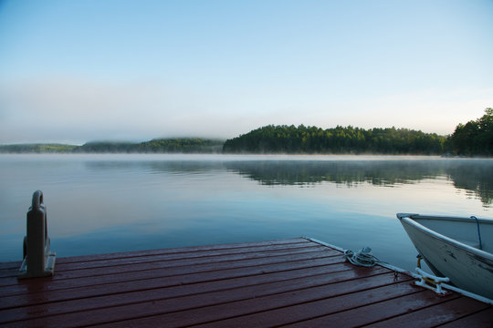 Muskoka dock and boat on a misty morning lake