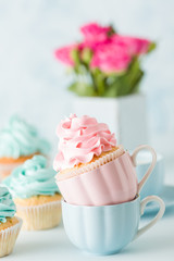 Blue pastel banner with decorated cupcakes, cup of coffe with milk and bouquet of pink roses.