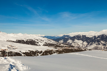 Obraz premium Fresh snow on ski pistes, covering valleys and peaks, with rugged mountain tops panorama, on a clear winter day, Les Trois Vallees, Alps, France .