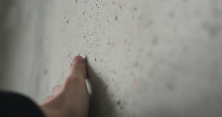 handheld of man hand touching concrete wall