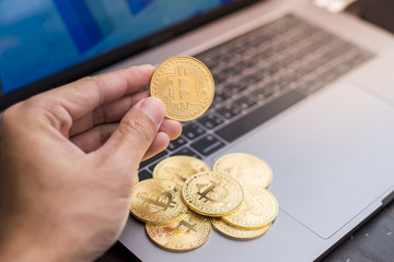 male hand holding  bitcoin on a laptop background.