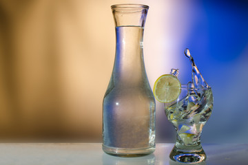 Splash water in a glass with a lemon and a bottle in beige tones