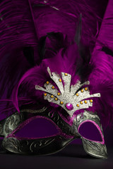 Carnival Venice purple mask with feathers on the black table.