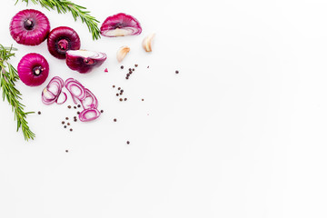 Red onion among spices rosemary, garlic, black peper on white background top view space for text