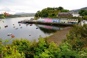 Fototapeta na wymiar Harbour of Portree with colorful houses and boats in bay, trees in the foreground. Isle of Skye, Scotland.