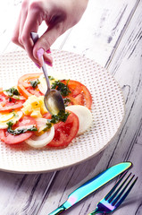 A woman cook pours a beautiful salad dressing from vegetable, olive, sunflower, corn oil and parsley, coriander, basil. Cooking healthy diet breakfast, lunch, dinner.
