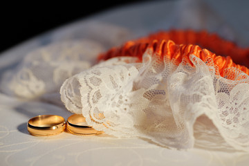 Wedding rings on white fabric framed with tulle with lace. Close-up. 