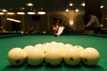 White billiard balls on a green cloth lined with a pyramid
