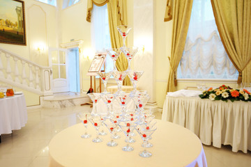 Pyramid with wine glasses on a table decorated with rose petals in the restaurant. Welcome drink at the wedding banquet.