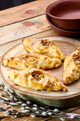 Traditional Russian, Ukrainian, Belarusian, Slavic pies with hole in center. Rasstegay - pastry with cabbage, meat, fish, mushrooms. Rustic pottery in the background. Branch of a blossoming willow.