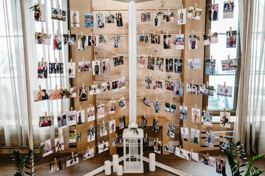 Romantic pictures of newlyweds and photos of holiday people hanging on clothesline by clothespins on the stand, garland. wedding decor.