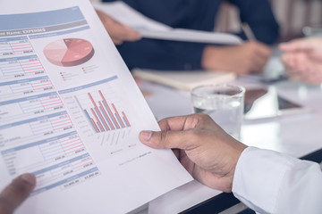 Top view hand of business team during meeting conference are working documents about the marketing plan and sales report finance of the company with laptop computer and smartphone tablet on work table