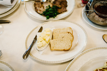 Bread, croutons and butter in a white plate on the table. A delicious stylish dish. Serves dinner on a festive table. Food on festive table at wedding banquet.