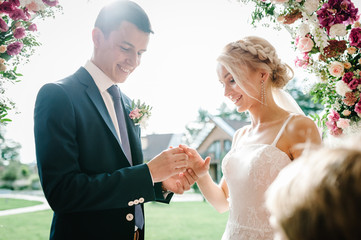 The handsome groom wears a wedding engagement golden ring on the finger of the attractive bride...