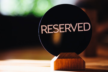 Reserved sign on restaurant table. Booked desk in cozy cafe against blurred background. Booking and...
