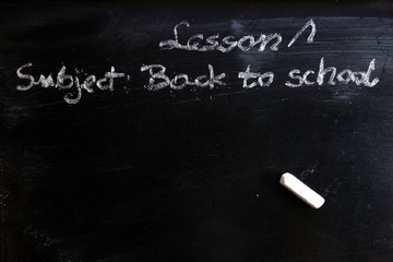 Education concept with first lesson subject - back to school written on chalkboard, copy space for your design