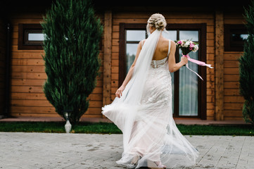 Fototapeta premium Portrait of an attractive bride with a wedding bouquet dancing and rotating back, spinning on a wedding ceremony.