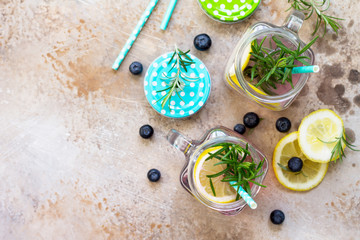 Homemade refreshing drink with blueberries, lemon and rosemary. The concept of proper nutrition and health or detoxification. Copy space, top view of a flat background.